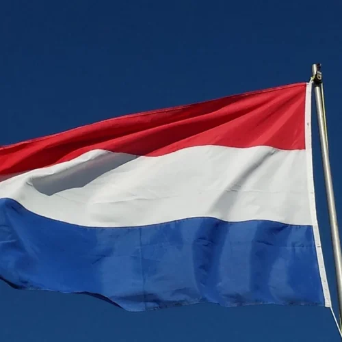 Nederlandse vlag aan een mast tegen een blauwe lucht